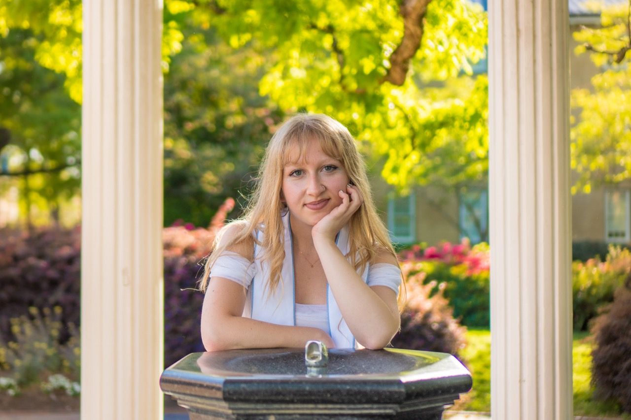 A grad at the Old Well leaning into the camera