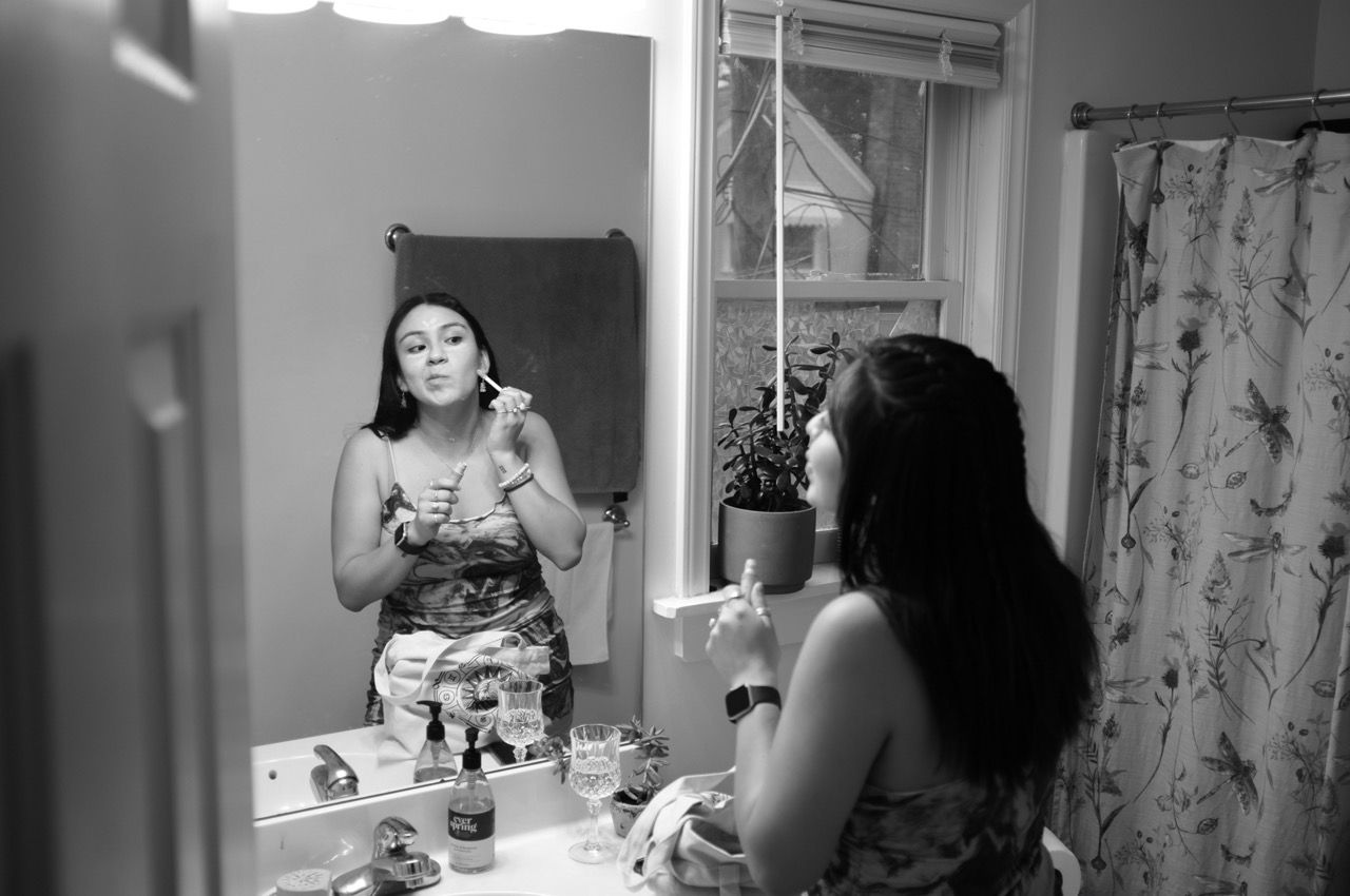 Black and white photo of someone getting ready in a mirror