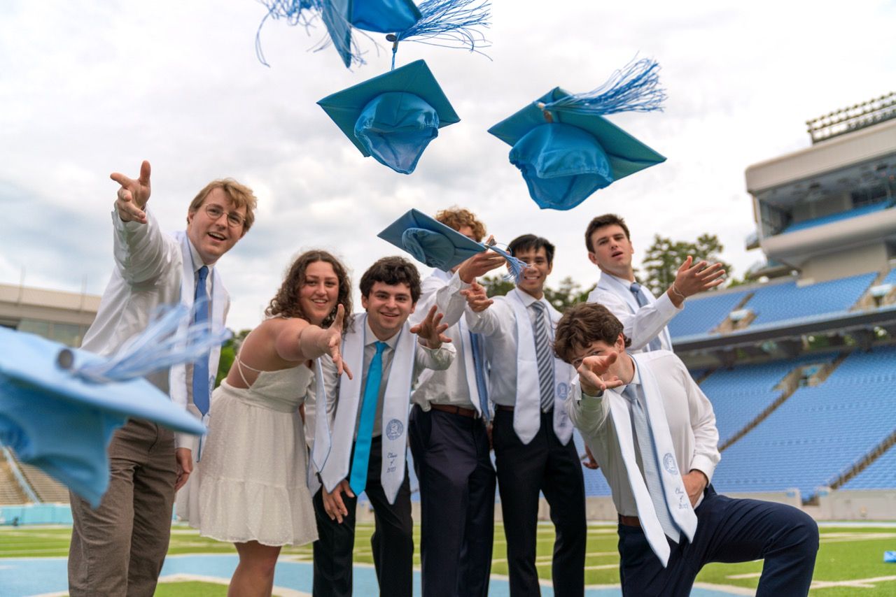 A group of seven grads throwing their caps