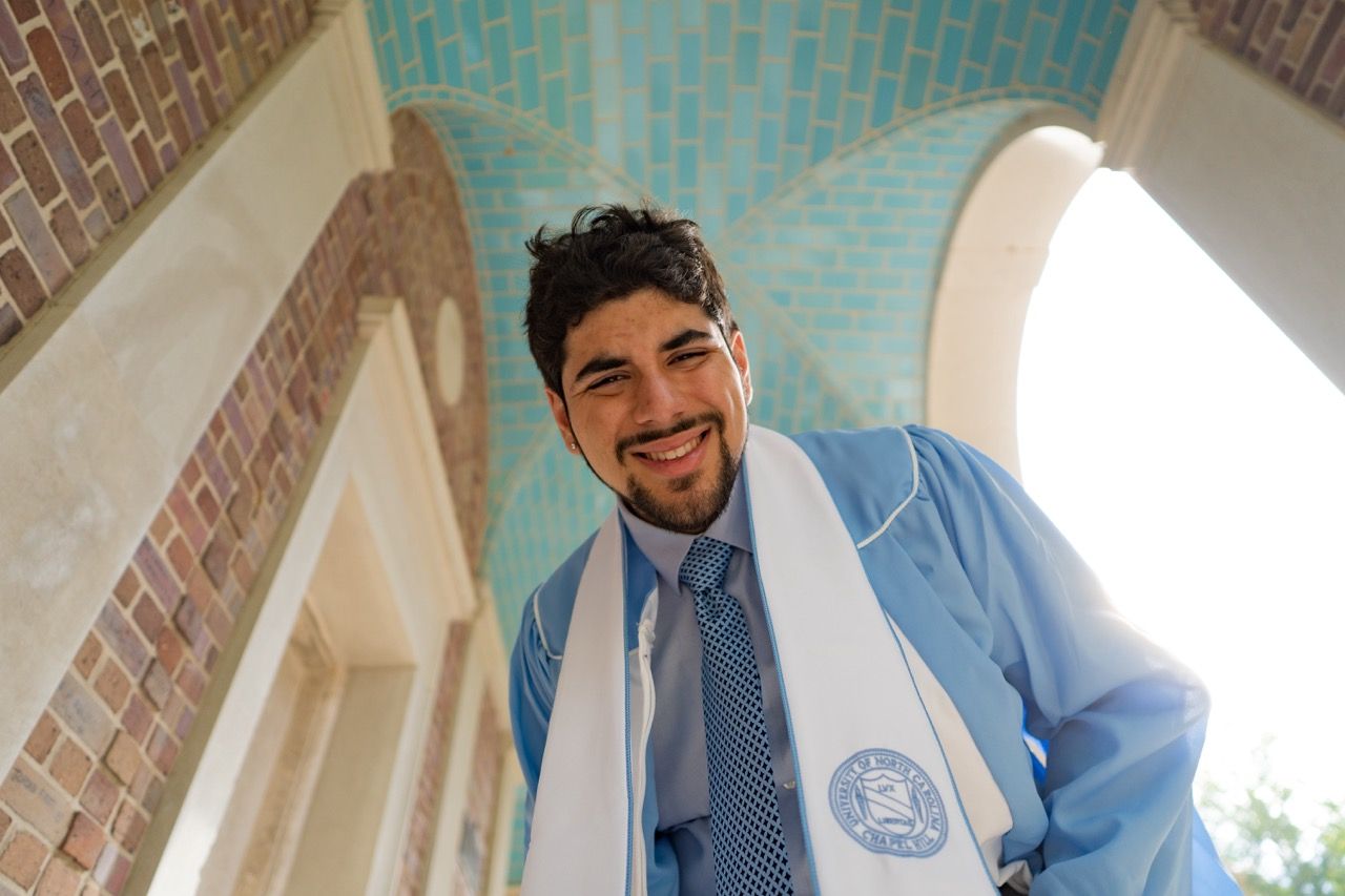 A grad leaning down and looking into the camera