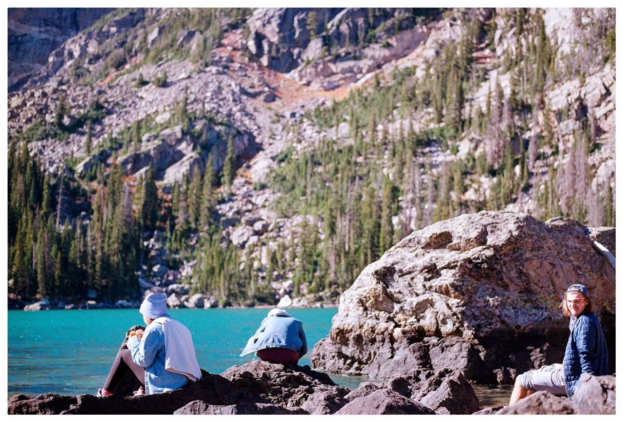 Hikers resting on rocks beside a turquoise alpine lake
